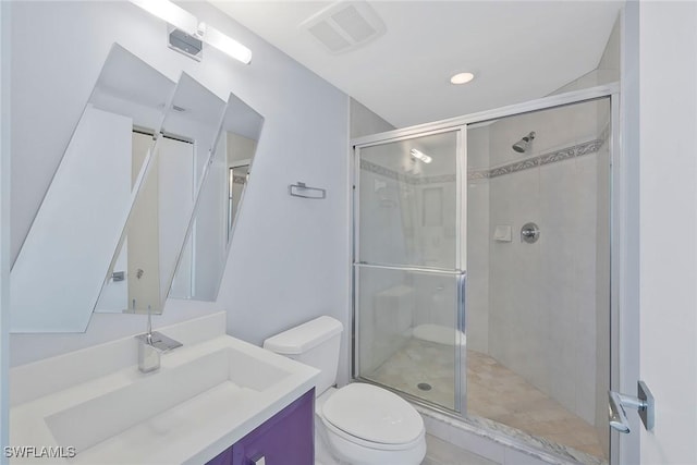 bathroom featuring vanity, a shower with shower door, and toilet