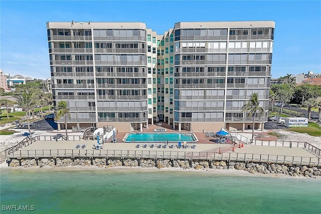 view of property with a community pool, a beach view, and a water view