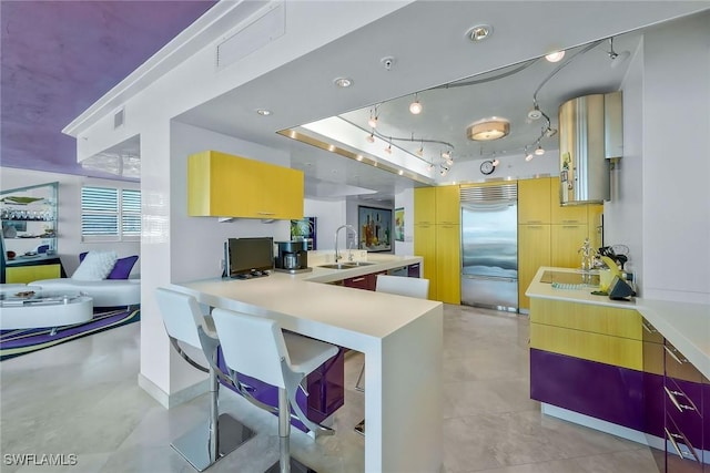 kitchen with sink, track lighting, kitchen peninsula, and stainless steel built in refrigerator