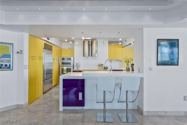 kitchen with a breakfast bar area, stainless steel appliances, kitchen peninsula, and light brown cabinets