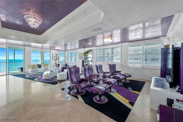 gym featuring plenty of natural light, a raised ceiling, a chandelier, and a water view