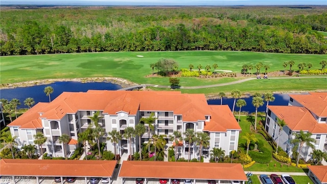 drone / aerial view with golf course view, a water view, and a view of trees