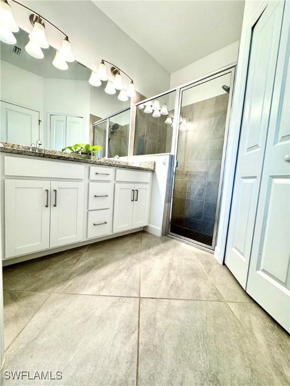 bathroom featuring vanity, tile patterned flooring, and a shower with door