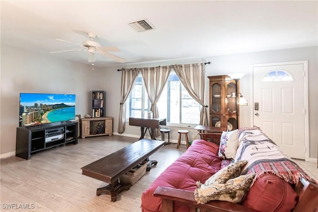 living area with visible vents, a ceiling fan, baseboards, and wood finished floors