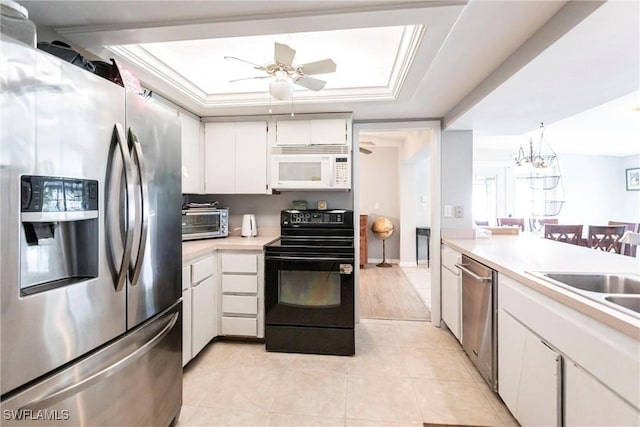 kitchen with ornamental molding, stainless steel appliances, a raised ceiling, and white cabinets