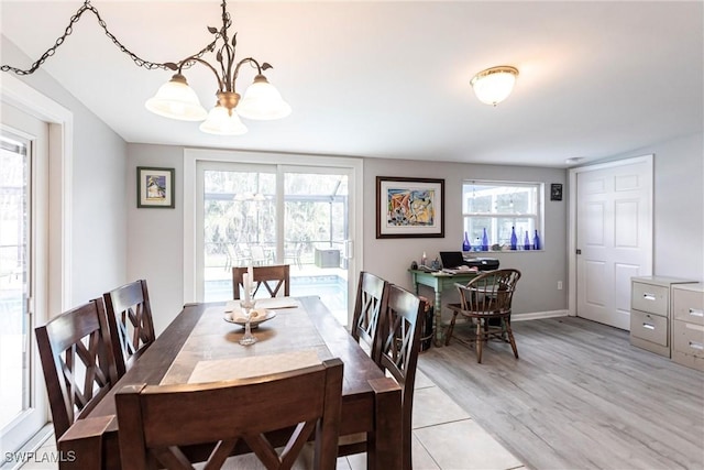 dining room featuring an inviting chandelier, a healthy amount of sunlight, light wood-style floors, and baseboards