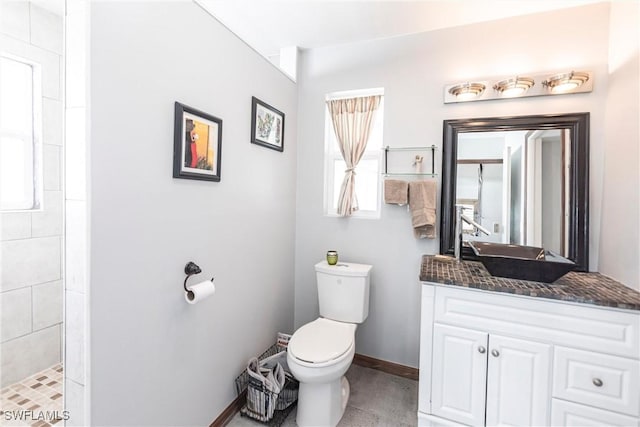 bathroom with vanity, a tile shower, and toilet