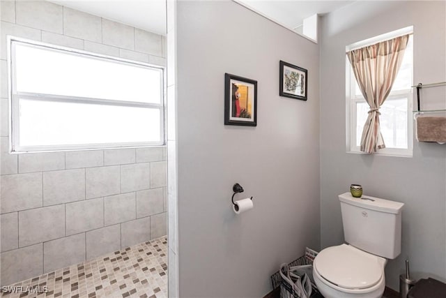 bathroom featuring tiled shower and toilet