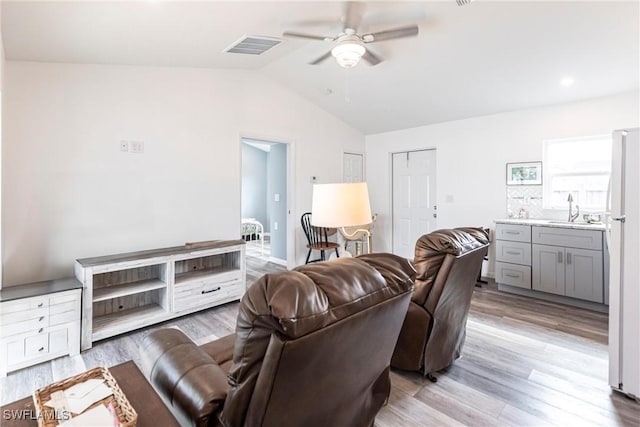 living room with lofted ceiling, sink, ceiling fan, and light wood-type flooring