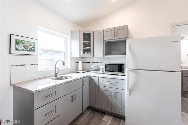 kitchen featuring sink, gray cabinetry, light stone counters, vaulted ceiling, and white fridge