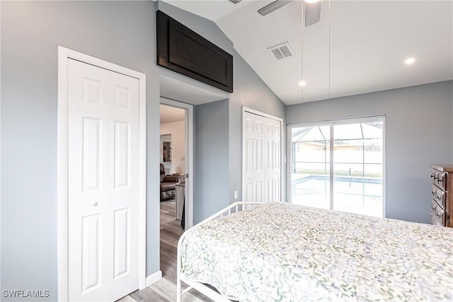 bedroom featuring two closets, wood-type flooring, ceiling fan, and vaulted ceiling