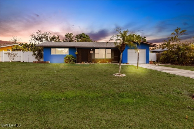 single story home featuring a garage, a lawn, concrete driveway, and fence