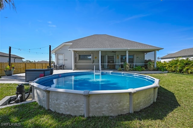 view of swimming pool with a yard and a hot tub