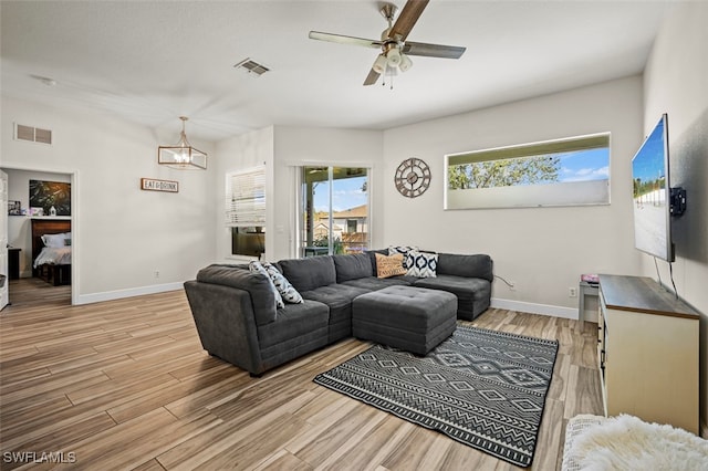 living room with ceiling fan with notable chandelier and light hardwood / wood-style floors