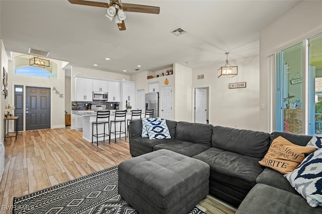 living room with ceiling fan and light hardwood / wood-style flooring