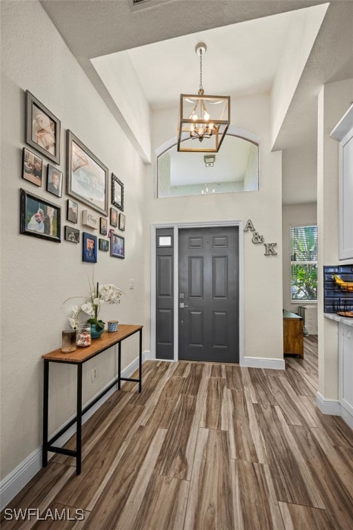 foyer with wood-type flooring and a notable chandelier