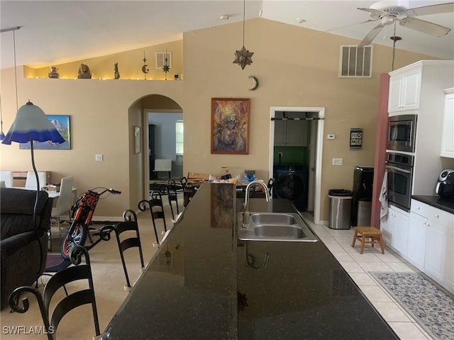 kitchen featuring sink, white cabinetry, light tile patterned floors, appliances with stainless steel finishes, and washer / clothes dryer