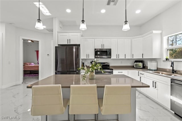 kitchen featuring sink, decorative light fixtures, stainless steel appliances, and a kitchen breakfast bar