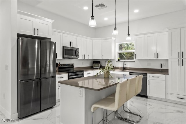 kitchen with a kitchen island, decorative light fixtures, white cabinets, and black appliances