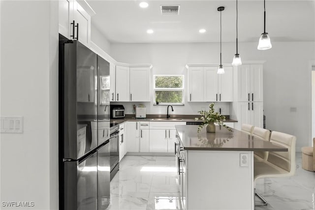 kitchen with a kitchen bar, sink, white cabinetry, a center island, and appliances with stainless steel finishes