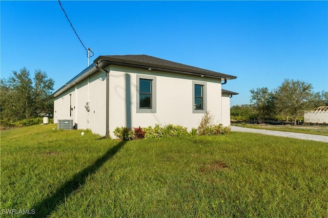 view of side of home featuring central AC and a yard