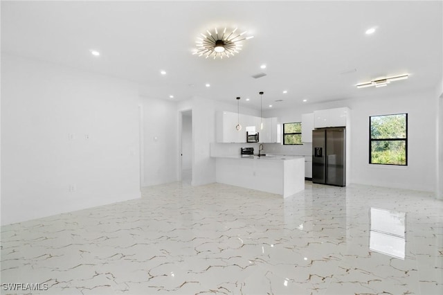 kitchen featuring sink, white cabinetry, black refrigerator with ice dispenser, kitchen peninsula, and pendant lighting