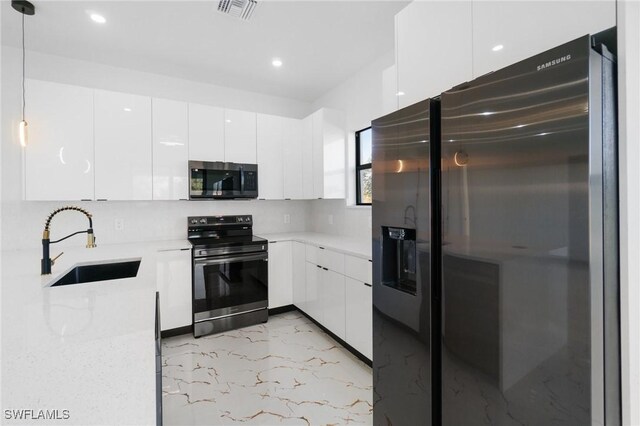 kitchen featuring pendant lighting, sink, appliances with stainless steel finishes, light stone counters, and white cabinets