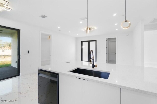 kitchen with decorative light fixtures, dishwasher, white cabinetry, sink, and light stone countertops