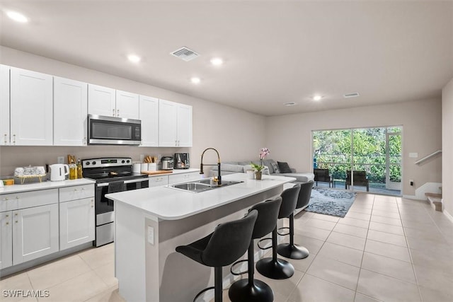 kitchen with sink, a breakfast bar area, white cabinetry, stainless steel appliances, and an island with sink