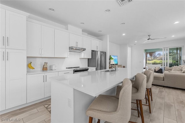 kitchen featuring appliances with stainless steel finishes, a kitchen breakfast bar, an island with sink, and white cabinets