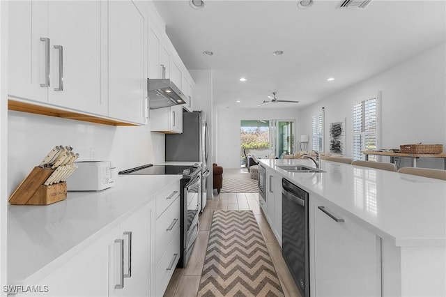 kitchen with sink, white cabinetry, stainless steel electric range oven, dishwasher, and wall chimney range hood