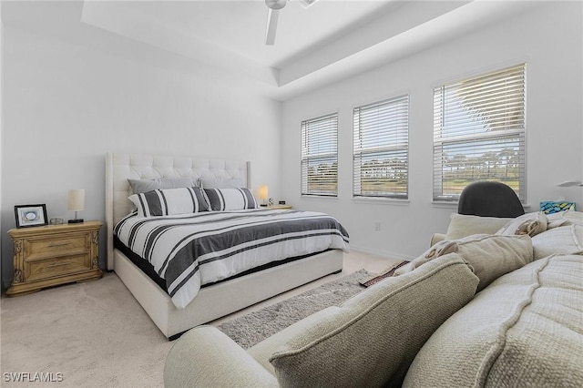 carpeted bedroom featuring ceiling fan and a tray ceiling