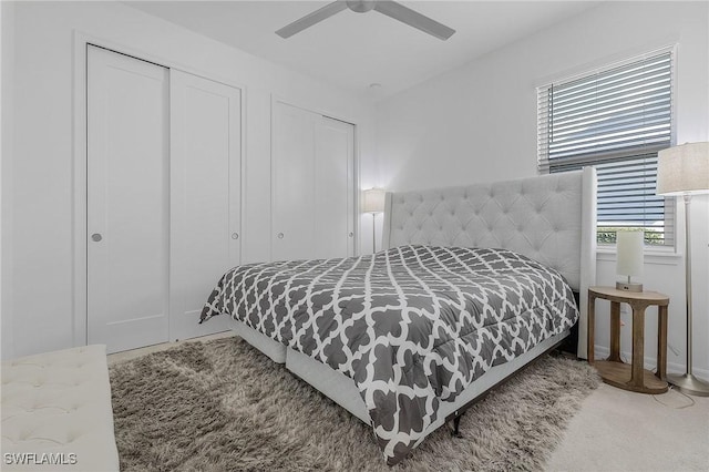 bedroom with ceiling fan and two closets