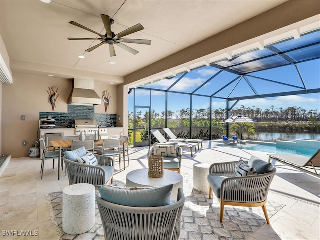 view of patio featuring exterior kitchen, a lanai, grilling area, ceiling fan, and a water view