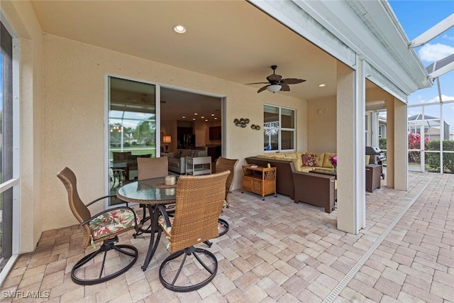 view of patio featuring ceiling fan, grilling area, an outdoor hangout area, and glass enclosure