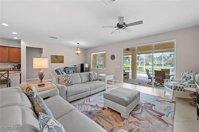 tiled living room featuring ceiling fan with notable chandelier