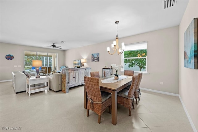 tiled dining room featuring ceiling fan with notable chandelier and a wealth of natural light