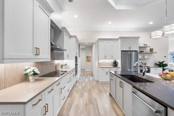 kitchen featuring sink, hanging light fixtures, ornamental molding, stainless steel appliances, and wall chimney range hood