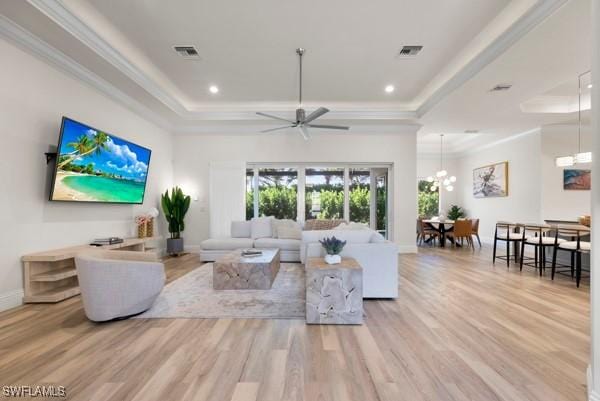 living room featuring crown molding, a tray ceiling, and light hardwood / wood-style flooring