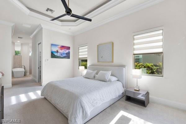 bedroom featuring connected bathroom, ceiling fan, a tray ceiling, crown molding, and light carpet