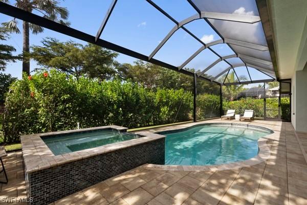 view of swimming pool with an in ground hot tub, a patio, and glass enclosure