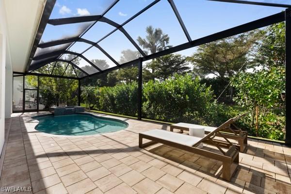 view of swimming pool featuring a patio and glass enclosure