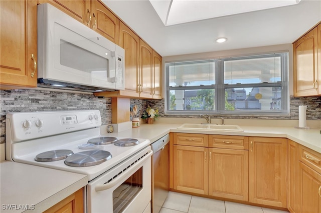 kitchen featuring tasteful backsplash, sink, light tile patterned floors, and white appliances