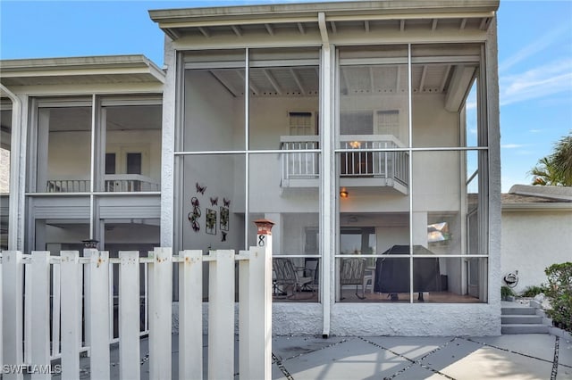 view of front facade featuring a balcony, fence, and a sunroom