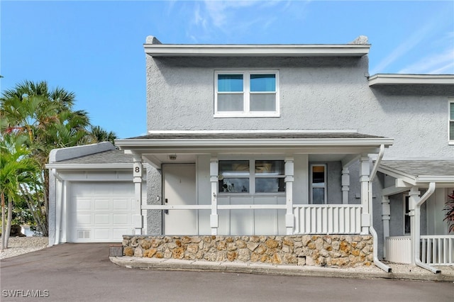 view of front of property with stucco siding, driveway, covered porch, and an attached garage