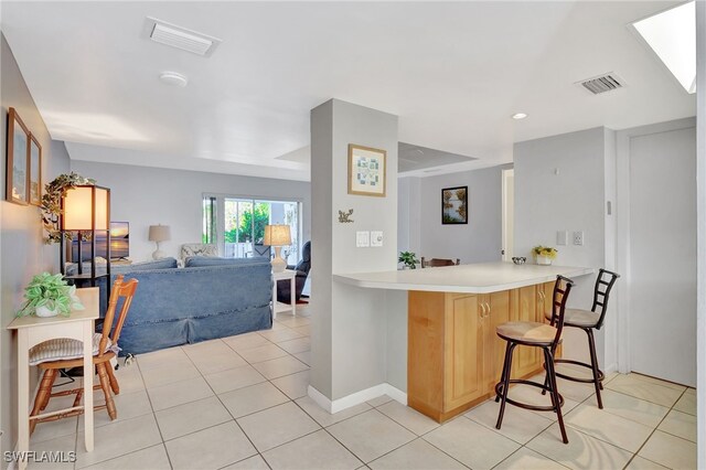 kitchen featuring light tile patterned floors, a kitchen breakfast bar, and kitchen peninsula