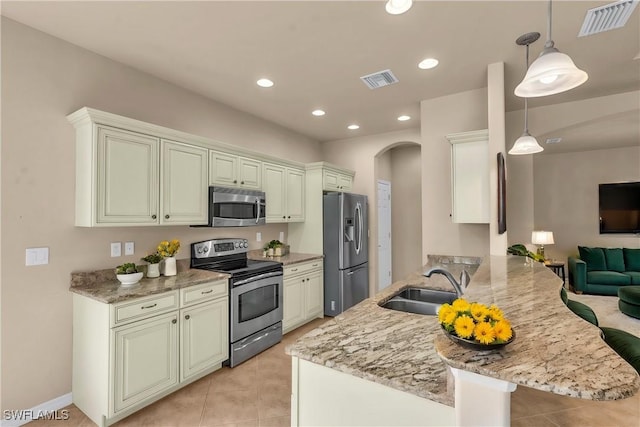 kitchen with sink, a breakfast bar, appliances with stainless steel finishes, hanging light fixtures, and kitchen peninsula