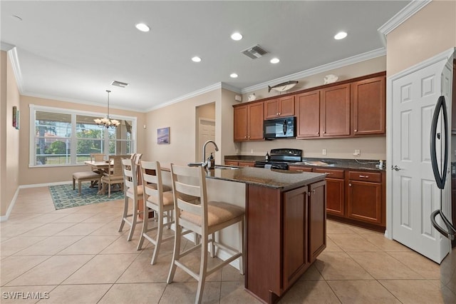 kitchen with sink, light tile patterned floors, an island with sink, pendant lighting, and black appliances