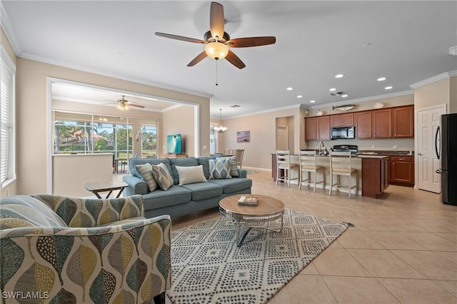 living room featuring light tile patterned floors, crown molding, ceiling fan with notable chandelier, and sink