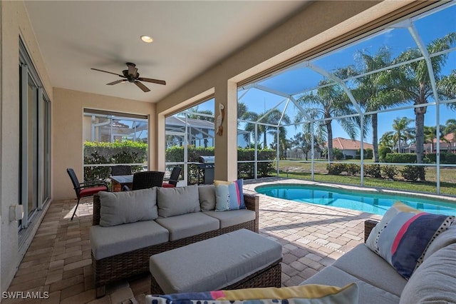 view of swimming pool featuring an outdoor living space, ceiling fan, glass enclosure, and a patio area